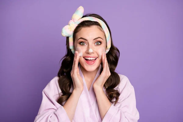 Foto de niña excitada joven disfrutar de procedimiento facial limpieza de espuma sonrisa feliz aislado sobre fondo de color violeta —  Fotos de Stock