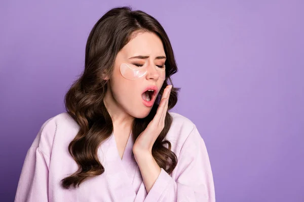 Фото молодой привлекательной сонной девушки зевает открытым ртом использование под повязками глаз изолированы на фиолетовом фоне цвета — стоковое фото