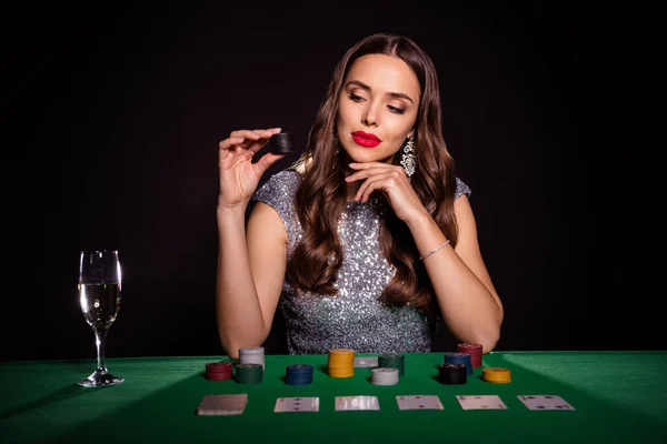Photo of minded charming lady sit poker table hold stack chip wear glossy dress isolated black color background — Stock Photo, Image