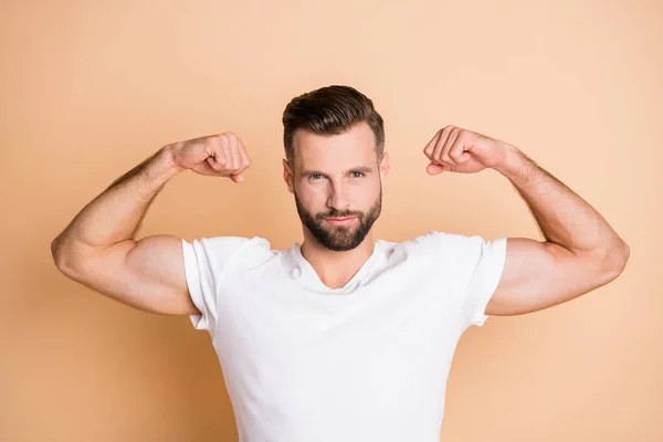 Foto van jonge knappe man opgeheven handen tonen biceps sportman geïsoleerd over beige kleur achtergrond — Stockfoto