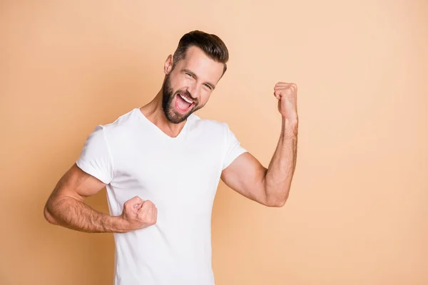 Foto di giovane uomo eccitato felice sorriso positivo divertimento gioia godere pugni mani celebrare vittoria obiettivo isolato su sfondo di colore beige — Foto Stock