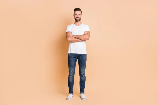 Full length photo of young handsome man happy positive smile confident crossed hands isolated over beige color background — Stock Photo, Image