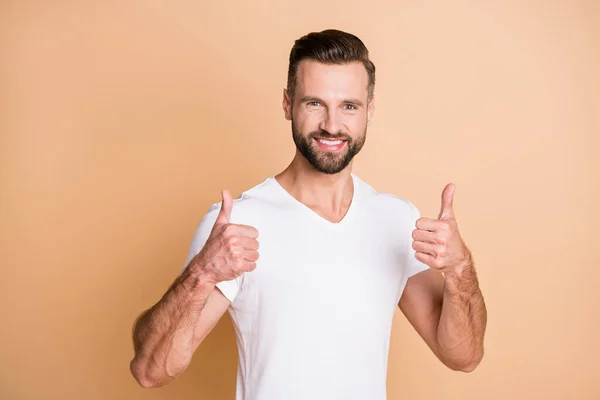 Foto de joven guapo hombre feliz sonrisa positiva mostrar pulgar hacia arriba como fresco anuncio perfecto aislado sobre fondo de color beige — Foto de Stock