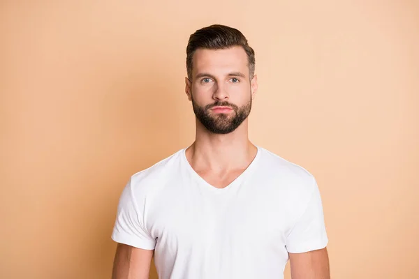 Foto de joven guapo rastrojo hombre serio confiado usar camiseta blanca aislada sobre fondo de color beige — Foto de Stock