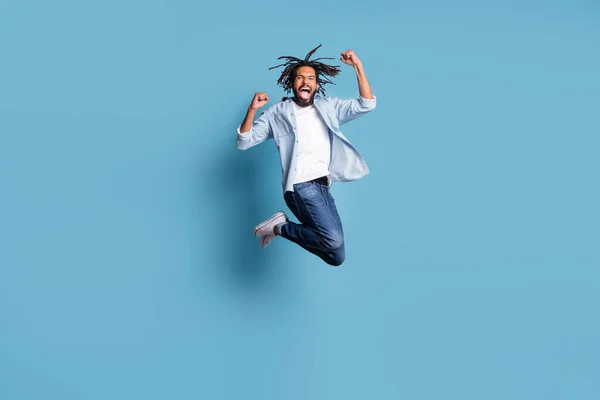 Foto de cuerpo entero de una persona de piel oscura asombrada saltando puños hasta la boca abierta celebran aislado sobre fondo de color azul — Foto de Stock