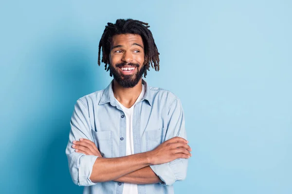 Portret van een leuke vrolijke man in jeans shirt gevouwen armen kijken opzij kopieerruimte geïsoleerd over helder blauwe kleur achtergrond — Stockfoto