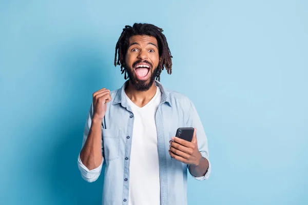 Retrato de cara feliz sorte atraente usando gadget navegar mídia como seguir se divertindo isolado sobre fundo de cor azul brilhante — Fotografia de Stock