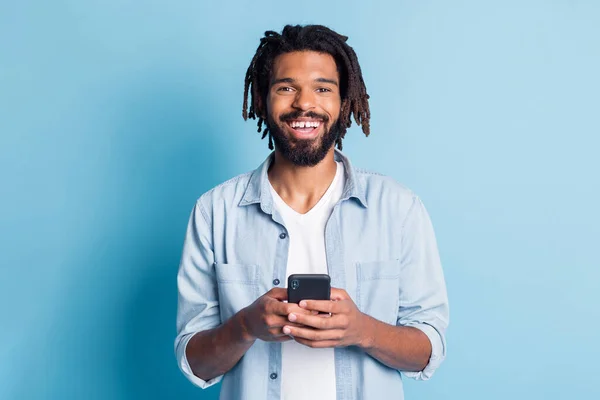 Retrato de chico alegre atractivo alegre utilizando dispositivo navegar por los medios de tiempo libre aislado sobre fondo de color azul brillante — Foto de Stock