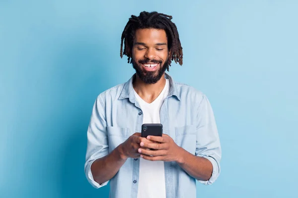 Retrato de chico alegre enfocado atractivo usando dispositivo de chat de tiempo libre aislado sobre fondo de color azul brillante — Foto de Stock