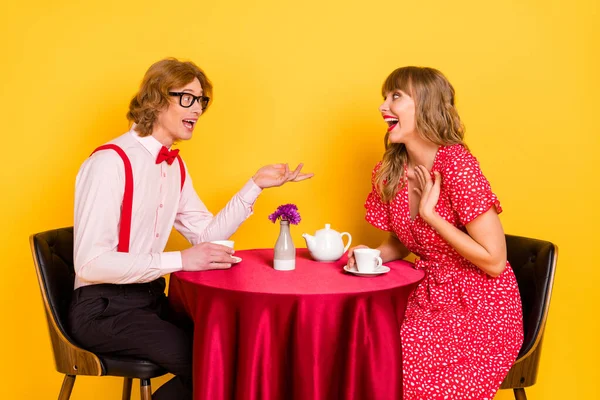 Foto retrato de casal encantador sentado no café tendo conversação bebendo chá rindo isolado vívido cor amarela fundo — Fotografia de Stock