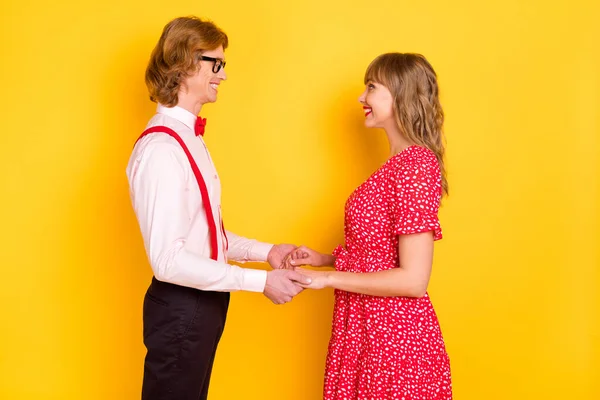 Foto porträtt av glada vackra par tittar på varandra att hålla händerna Alla hjärtans dag isolerad på pulserande gul bakgrund — Stockfoto