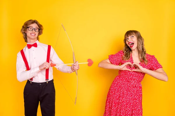 Foto retrato de cara com arco de seta e menina funky mostrando dedos do coração se apaixonando isolado no fundo amarelo brilhante — Fotografia de Stock