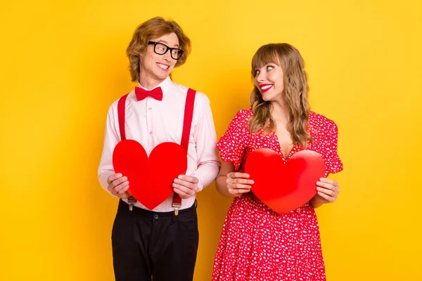 Foto retrato de namorado namorada mantendo corações no dia dos namorados olhando uns aos outros isolado no fundo amarelo brilhante — Fotografia de Stock