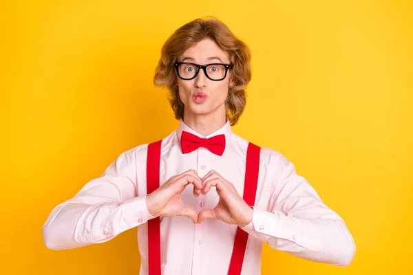 Foto retrato de friki con pelo rojo enviando beso de aire mostrando dedos del símbolo del corazón aislados sobre fondo amarillo vivo — Foto de Stock