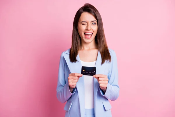 Foto de joven sonriente hermosa chica atractiva alegre celebrar ojo guiño tarjeta de crédito azul aislado sobre fondo de color rosa —  Fotos de Stock