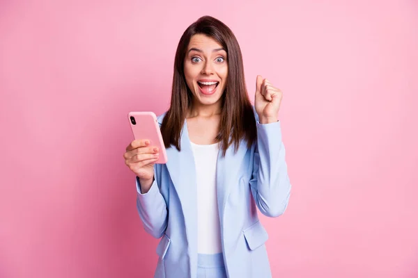 Photo de jeune fille attrayante sourire heureux poings étonnés main gagner excité utiliser téléphone cellulaire isolé sur fond de couleur rose — Photo