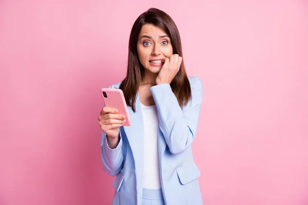 Фото молодой красивой женщины кусать пальцы нервной паники неудачу использования смартфона изолированы на розовом фоне — стоковое фото
