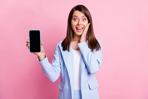 Фотографія молодої дівчини збуджена здивованою щасливою посмішкою тримайте мобільний телефон дотик щоки ізольовані на рожевому кольоровому фоні — стокове фото