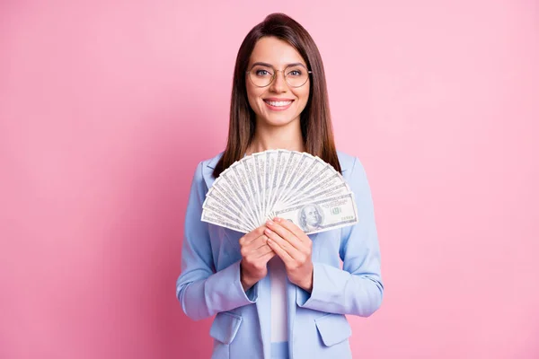 Foto ritratto di donna sorridente che tiene fan di dollari in due mani isolate su sfondo rosa pastello — Foto Stock