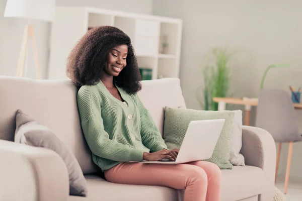 Perfil lado de la foto de la joven alegre mujer negra feliz sonrisa positiva sentarse sofá casa trabajo remoto programador portátil — Foto de Stock