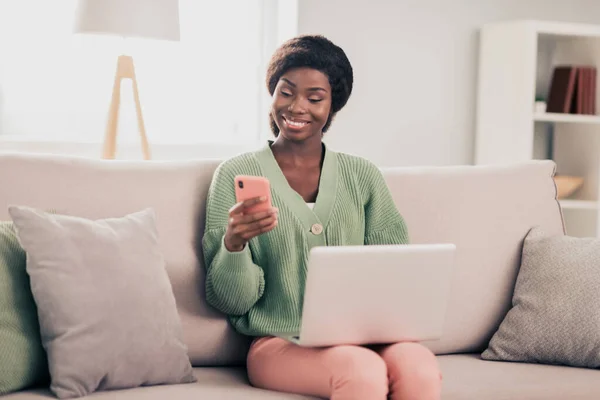 Retrato de atractiva chica alegre agente agente agente sentado en diván utilizando dispositivo portátil gadget en casa plana sala de estar interior — Foto de Stock