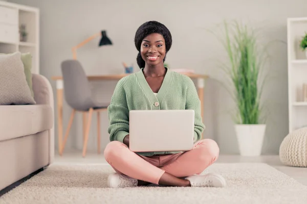 Foto de tamaño completo de la joven alegre chica negra feliz sonrisa positiva distancia trabajo ordenador portátil programador chat tipo correo electrónico sentarse piso casa — Foto de Stock