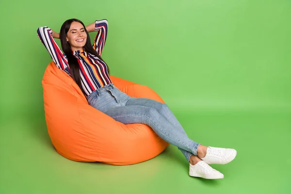 Portrait of attractive cheerful dreamy girl lying in soft bag chair resting isolated over green pastel color background — Stock Photo, Image