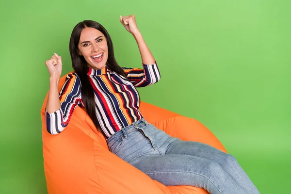 Portrait d'attrayant gai fille reposant dans la chaise célébrant la bonne chance isolé sur fond de couleur vert vif — Photo