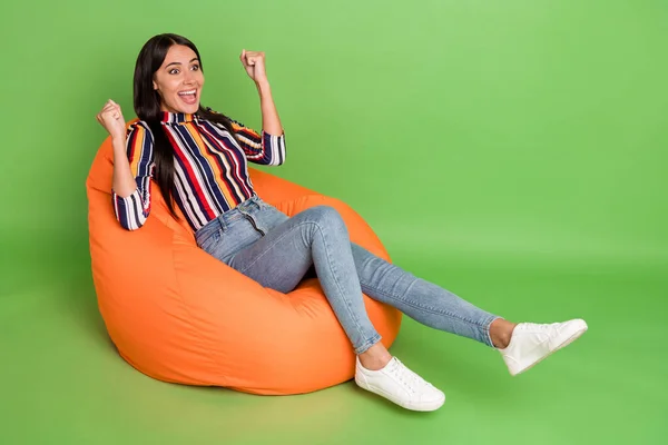 Retrato de menina atraente alegre surpreendido deitado em cadeira saco macio se divertindo regozijando isolado sobre fundo de cor verde brilhante — Fotografia de Stock