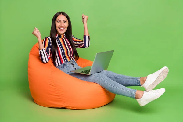 Profiel zijaanzicht portret van trendy mooie vrolijke meisje zitten in stoel met behulp van laptop plezier geïsoleerd over helder groene kleur achtergrond — Stockfoto