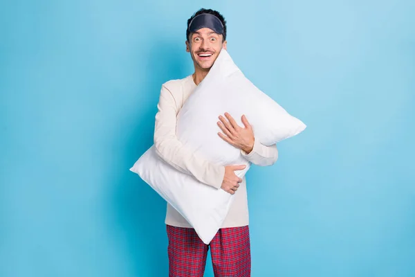 Porträtt av trevlig glad kille bär sömnkläder kläder hålla i händerna omfamna mjuk kudde isolerad över ljusblå färg bakgrund — Stockfoto