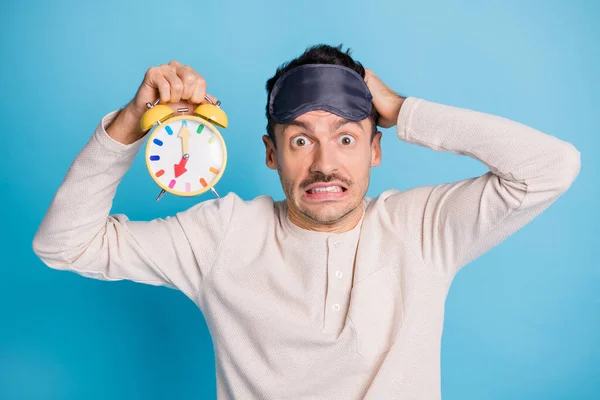 Foto retrato del culpable tocando la cabeza sosteniendo el reloj amarillo en una mano aislada sobre fondo de color azul vivo —  Fotos de Stock