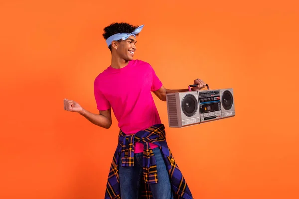 Foto retrato de jovens hipster dançando mantendo caixa boom vestindo headband roupas casuais isolado no fundo cor de laranja brilhante — Fotografia de Stock