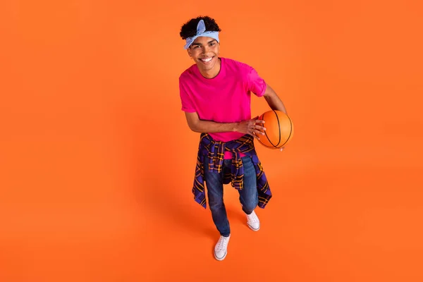 Oben über dem Hochwinkel Ansicht afroamerikanischer glücklicher Mann halten Basketball tragen enges Hemd isoliert auf orangefarbenem Hintergrund — Stockfoto