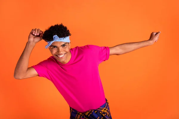 Foto retrato de un joven hipster sonriendo bailando en la discoteca el fin de semana aislado sobre un vibrante fondo de color naranja —  Fotos de Stock