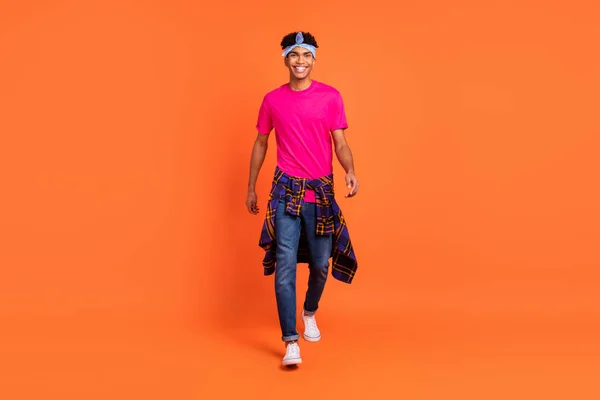 Full length body size foto jonge man in hoofdband glimlachen lopen voorwaarts geïsoleerde levendige oranje kleur achtergrond — Stockfoto