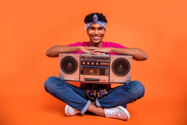 Longitud completa cuerpo tamaño foto de hombre joven con sentado mantener boom box sonriendo aislado color naranja vivo fondo —  Fotos de Stock