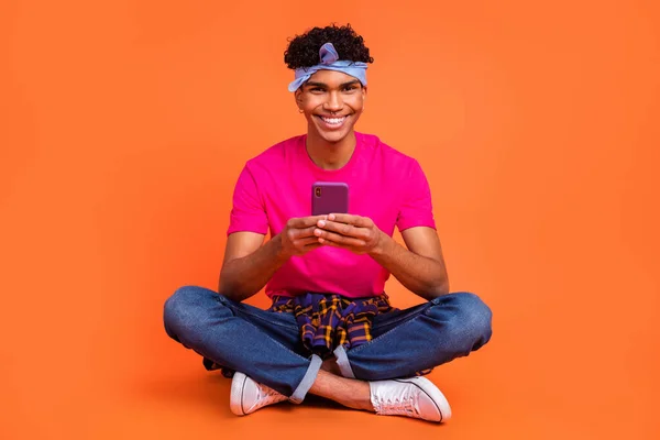 Volledige lichaamsomvang foto van jonge hipster houden mobiele telefoon met behulp van sociale media geïsoleerde levendige oranje kleur achtergrond — Stockfoto