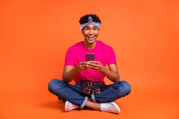 Volledige lichaamslengte foto van verbaasde man lezen nieuws met mobiele telefoon lachen geïsoleerde levendige oranje kleur achtergrond — Stockfoto