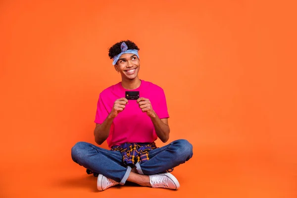 Volledige lichaamslengte foto van jonge hipster tonen bank kaart kijken lege ruimte geïsoleerd op fel oranje kleur achtergrond — Stockfoto