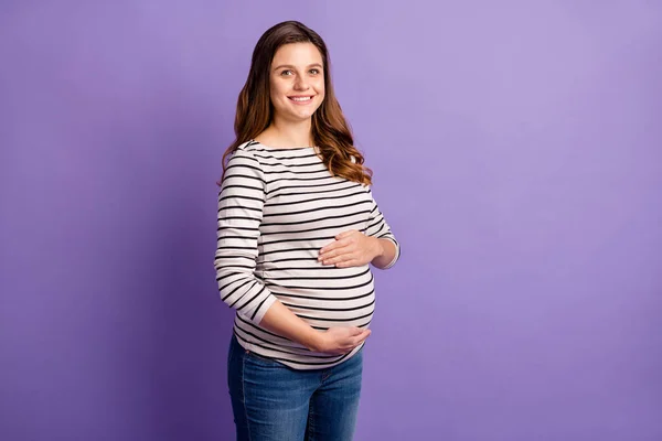 Фотопортрет беременной женщины, держащей живот изолирован на ярком фиолетовом фоне — стоковое фото
