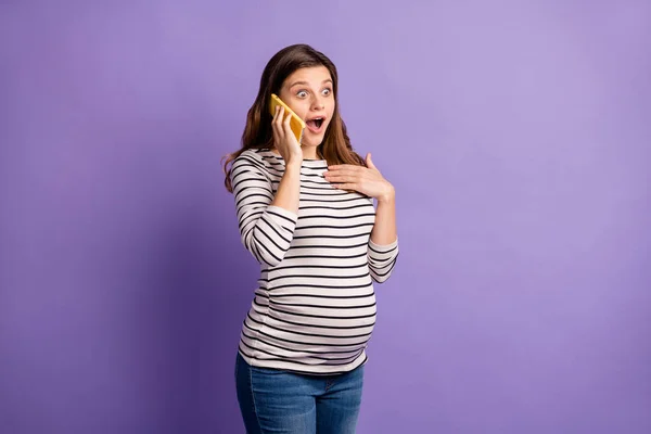 Retrato fotográfico de una mujer embarazada sorprendida hablando por teléfono aislada sobre fondo violeta vivo — Foto de Stock