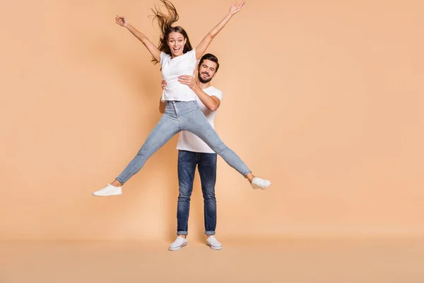 Volledige lengte foto van twee vrolijke mensen man handen houden dame maken ster figuur geïsoleerd op beige kleur achtergrond — Stockfoto