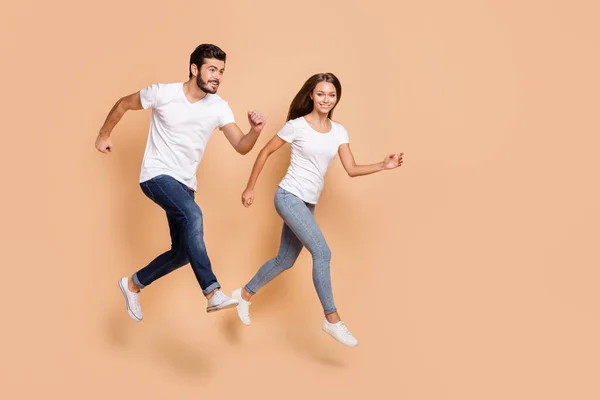 Teljes test profil oldalán fotó a fiatal pár boldog mosoly ugrás futni siet eladó elszigetelt bézs színű háttér — Stock Fotó