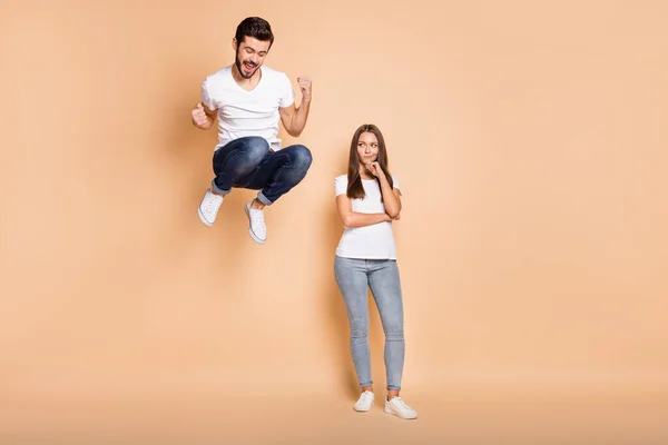 Foto de corpo inteiro do jovem casal ele feliz saltar para cima alegrar vitória ela infeliz triste isolado sobre fundo de cor bege — Fotografia de Stock