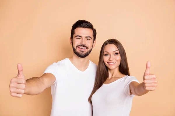 Foto van zoete zelfverzekerde echtgenoot vrouw dragen witte t-shirts knuffelen tonen duimen tot geïsoleerde beige kleur achtergrond — Stockfoto