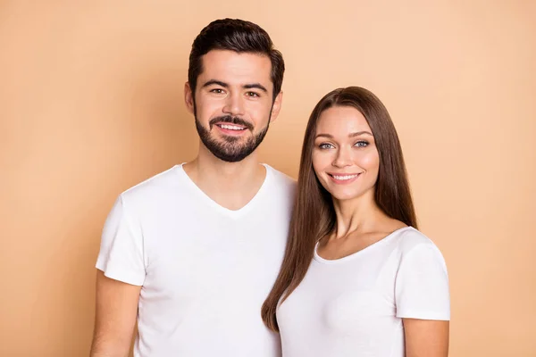 Foto van vrij schattig getrouwd paar gekleed witte t-shirts glimlachen omarmen geïsoleerde beige kleur achtergrond — Stockfoto