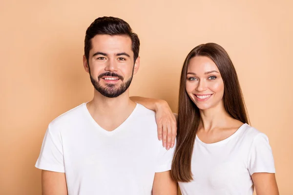 Foto de bonito bonito marido esposa desgaste branco t-shirts sorriso braço ombro isolado bege cor fundo — Fotografia de Stock