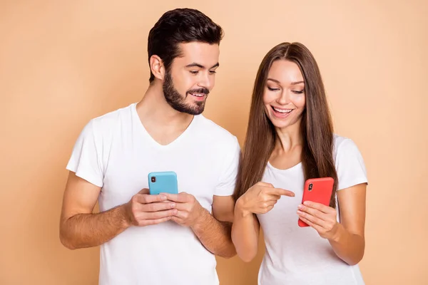 Photo de doux couple marié habillé t-shirts blancs regardant dispositif moderne pointant isolé fond de couleur beige — Photo