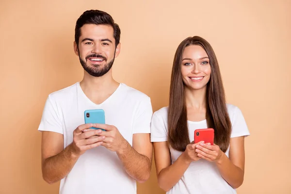 Foto di giovane coppia sposata felice sorriso positivo utilizzare cellulare tipo di chat sms isolato su sfondo di colore beige — Foto Stock